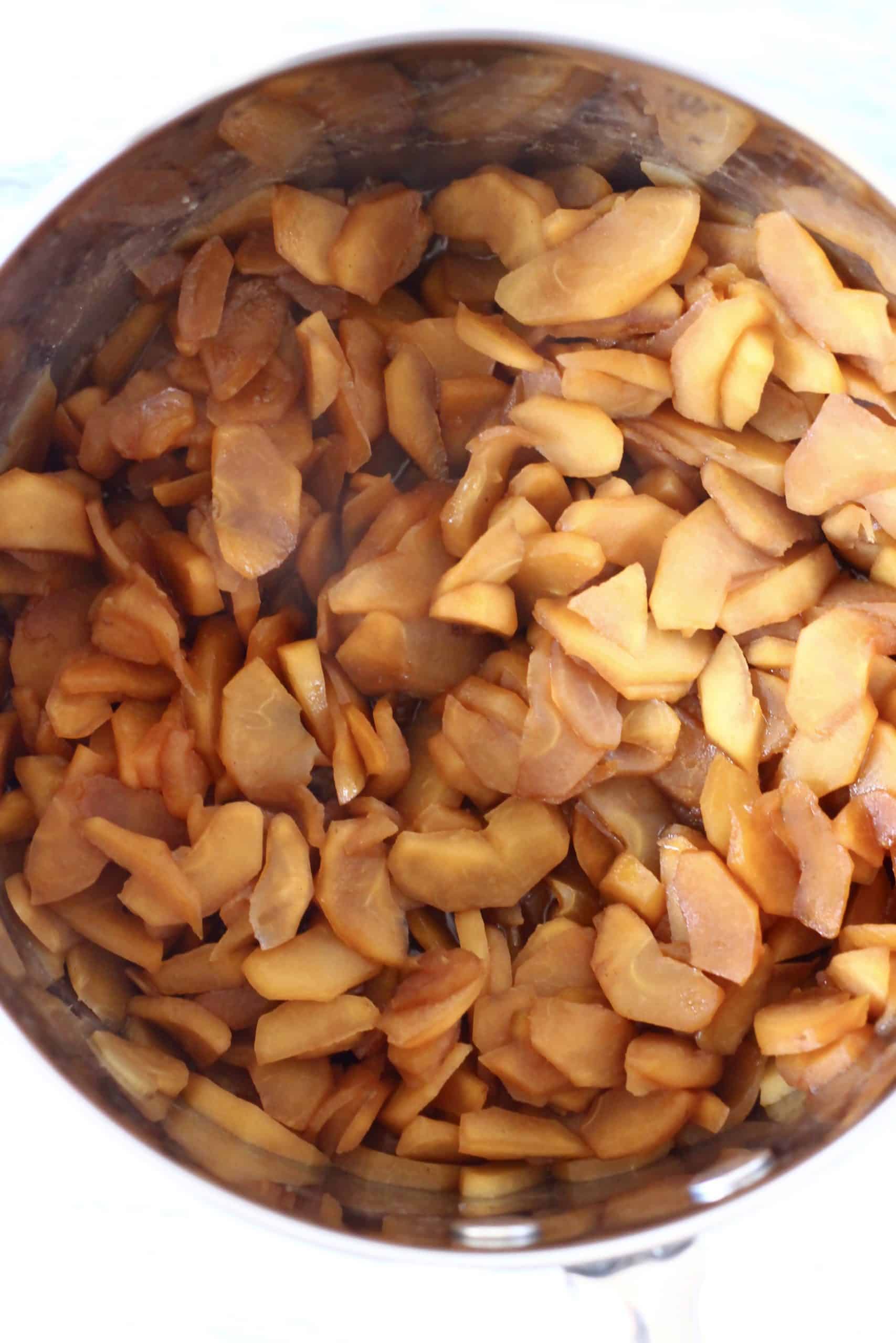 Cooked sliced apples with coconut sugar and cinnamon in a silver pan
