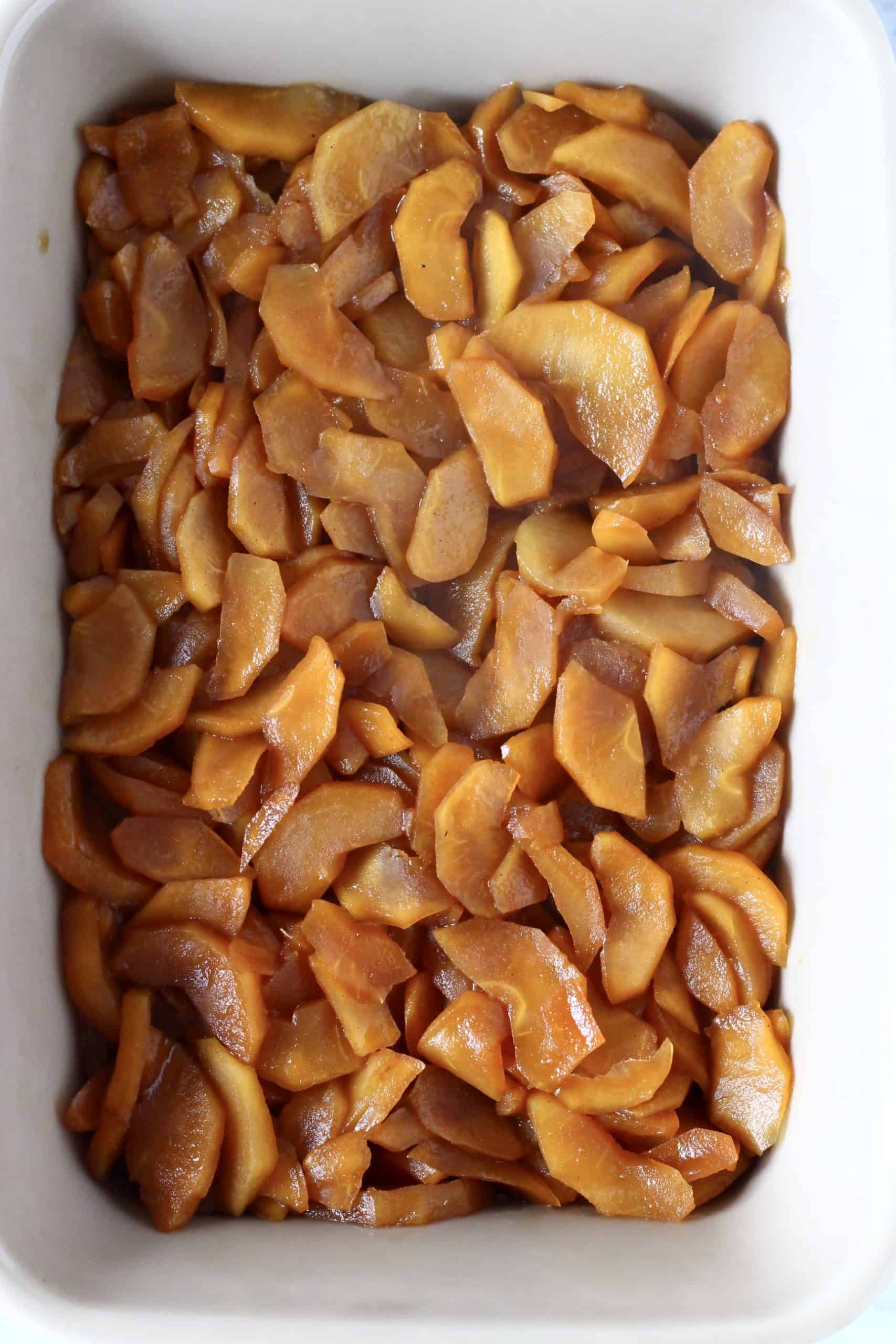 Cooked sliced apples with coconut sugar and cinnamon in a rectangular baking dish