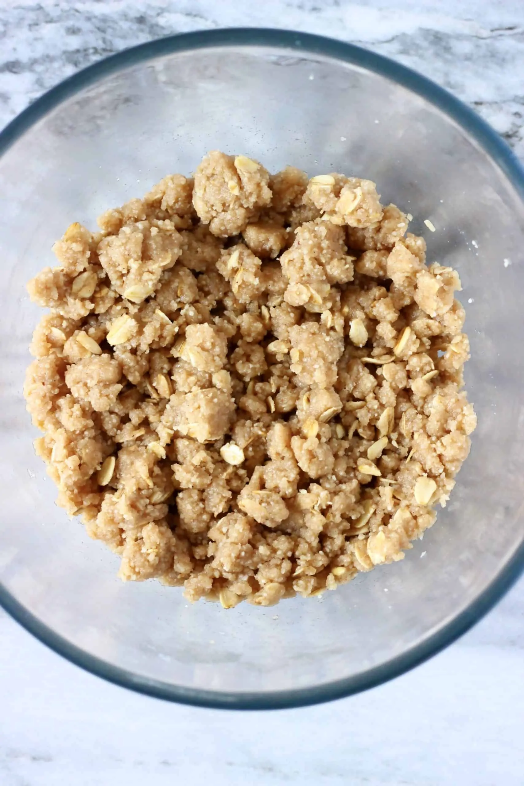 Raw crumble topping with oats in a glass bowl