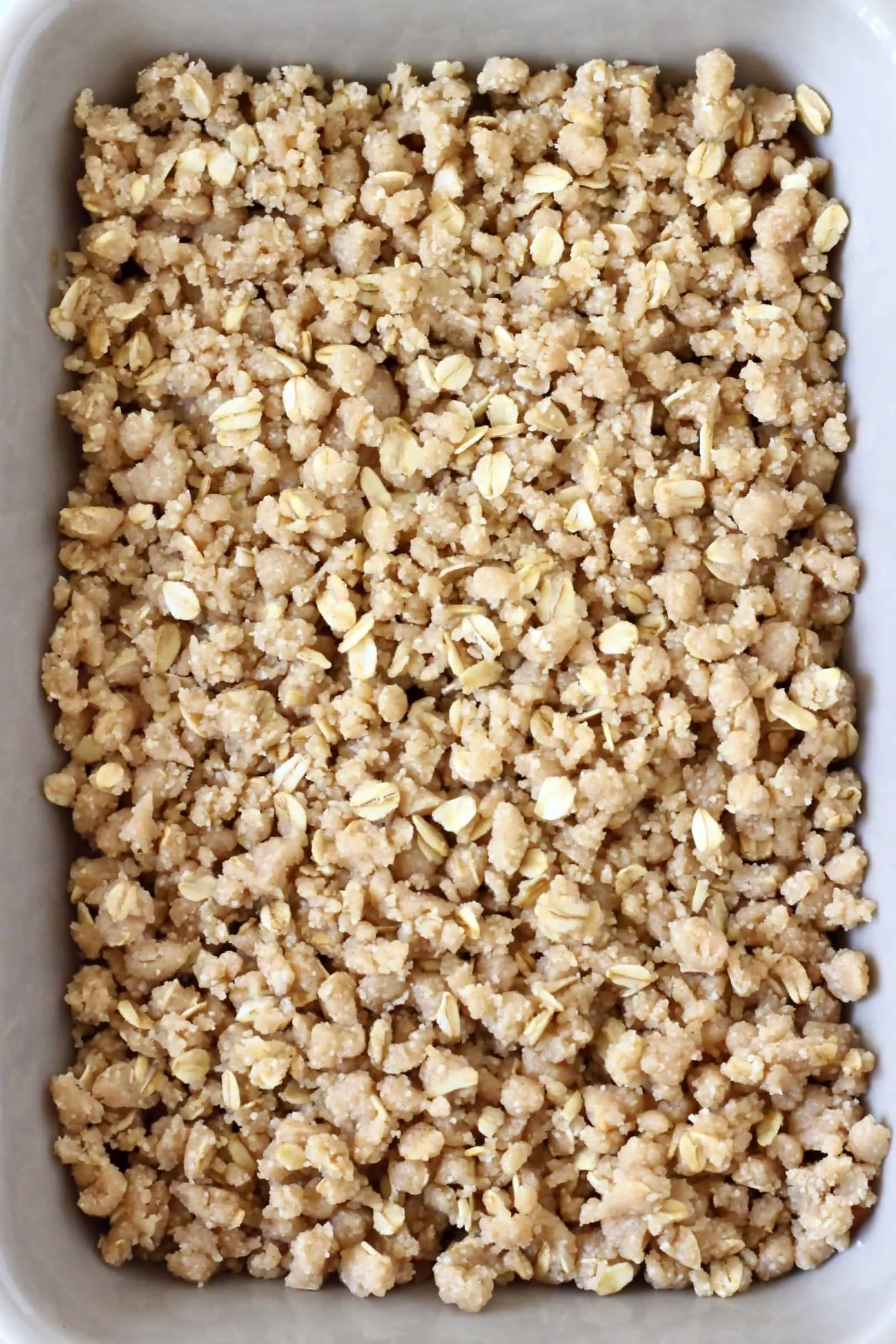 Raw gluten-free vegan crumble mixture with oats in a rectangular baking dish
