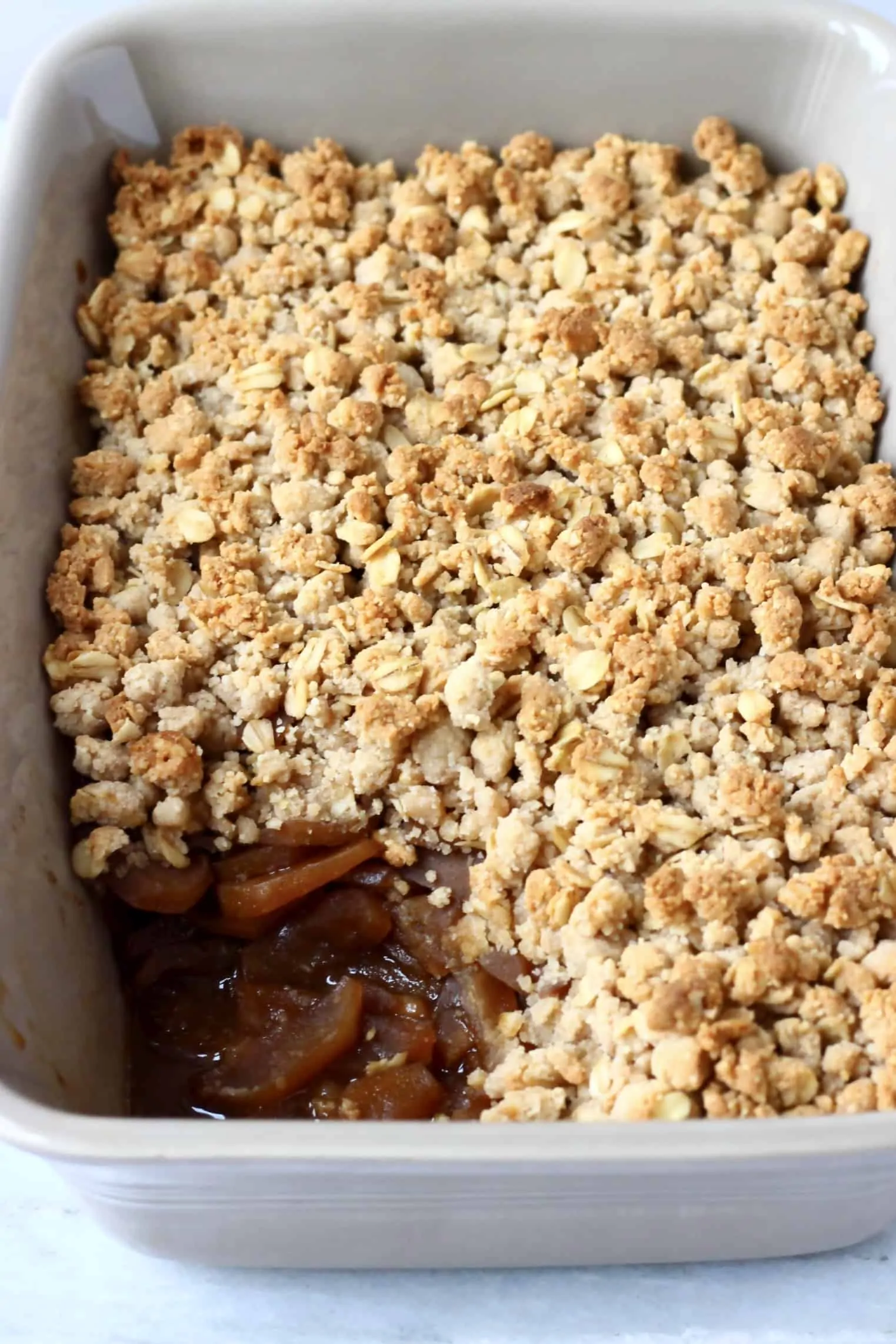 Gluten-free vegan apple crumble in a rectangular baking dish with a portion cut out