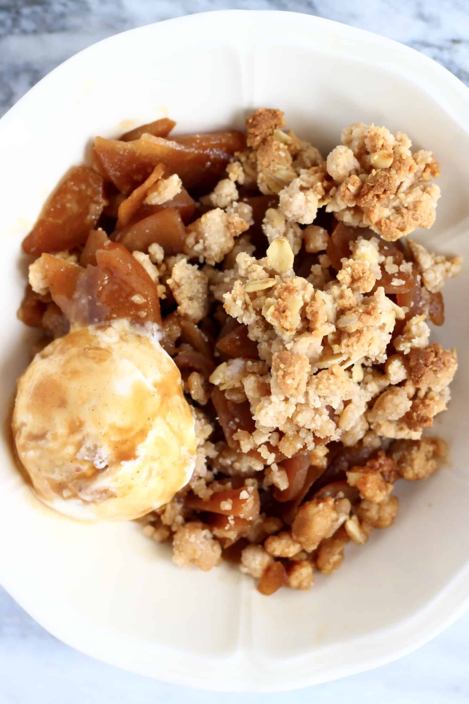 Gluten-free vegan apple crumble with a scoop of ice cream in a bowl