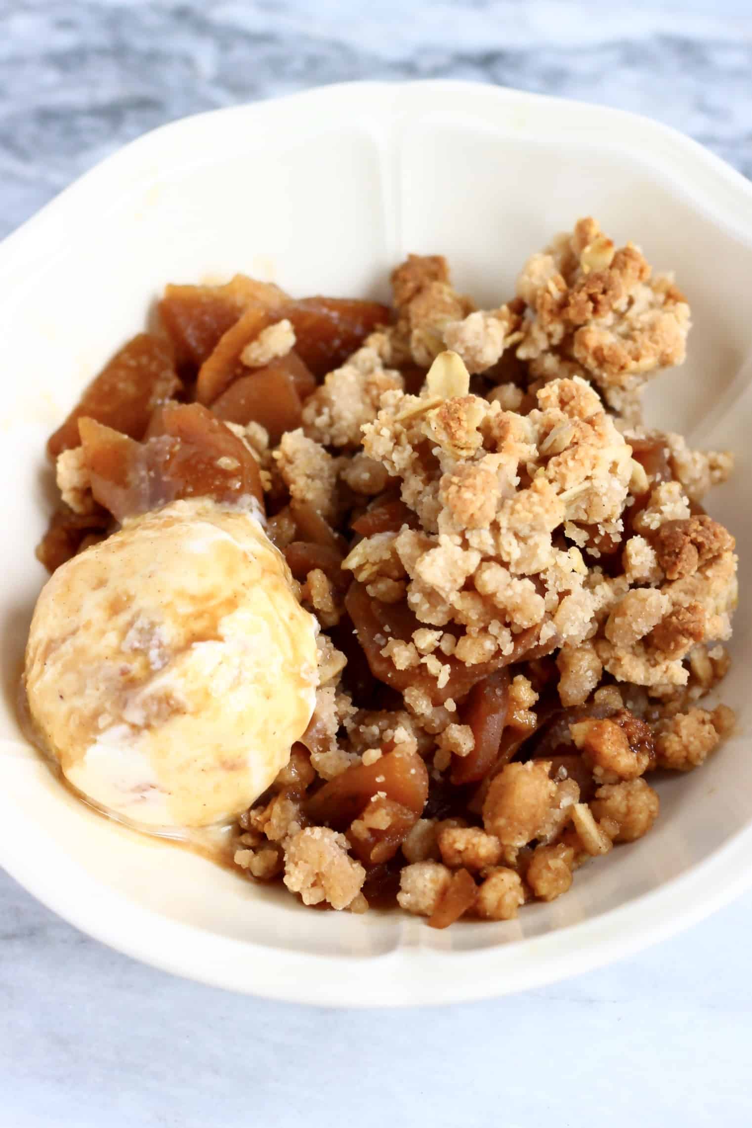 Gluten-free vegan apple crumble with a scoop of ice cream in a bowl