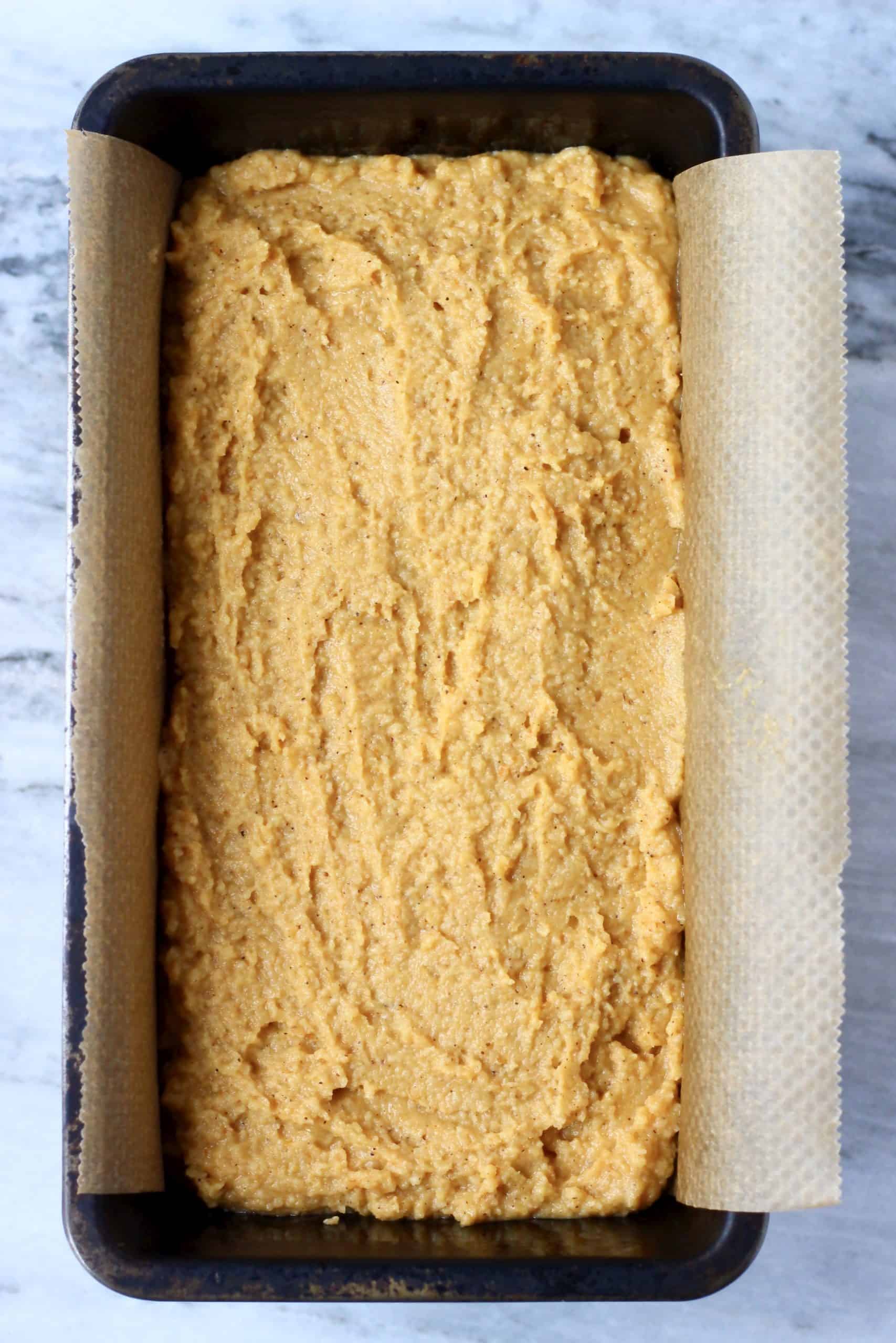 Gluten-free vegan pumpkin bread batter in a loaf tin lined with baking paper