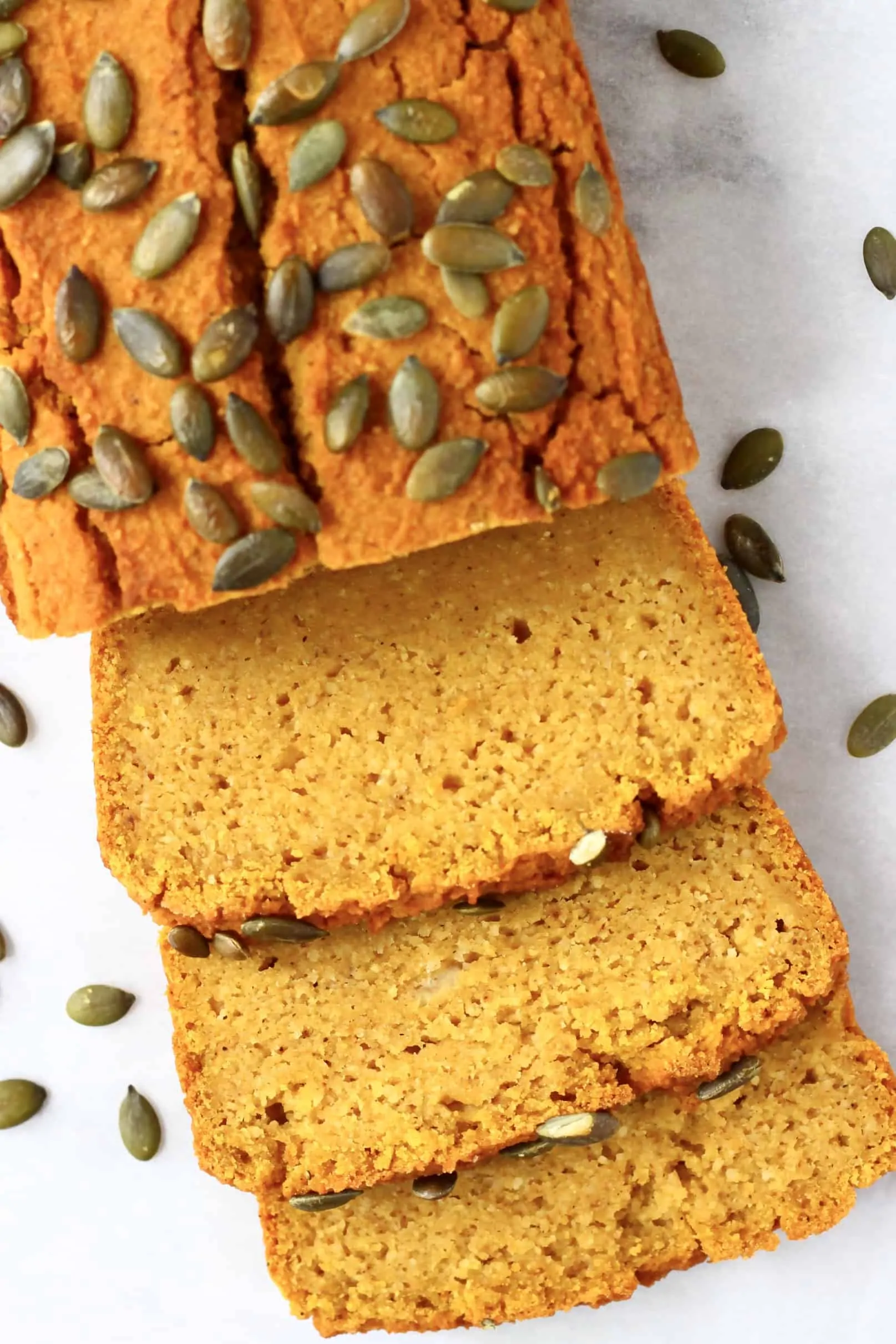 A loaf of gluten-free vegan pumpkin bread with three slices next to it