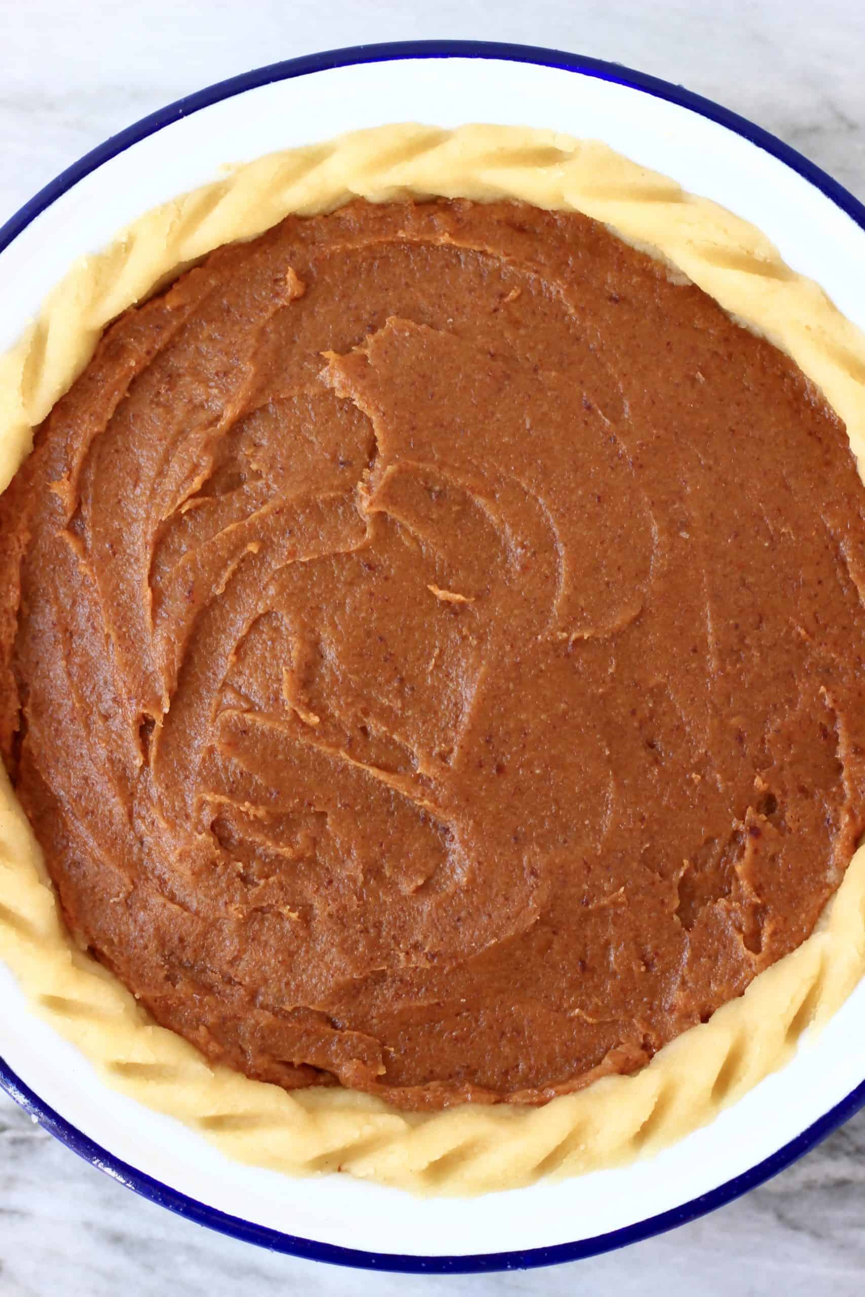 Pecan pie filling in a raw pie crust in a pie dish