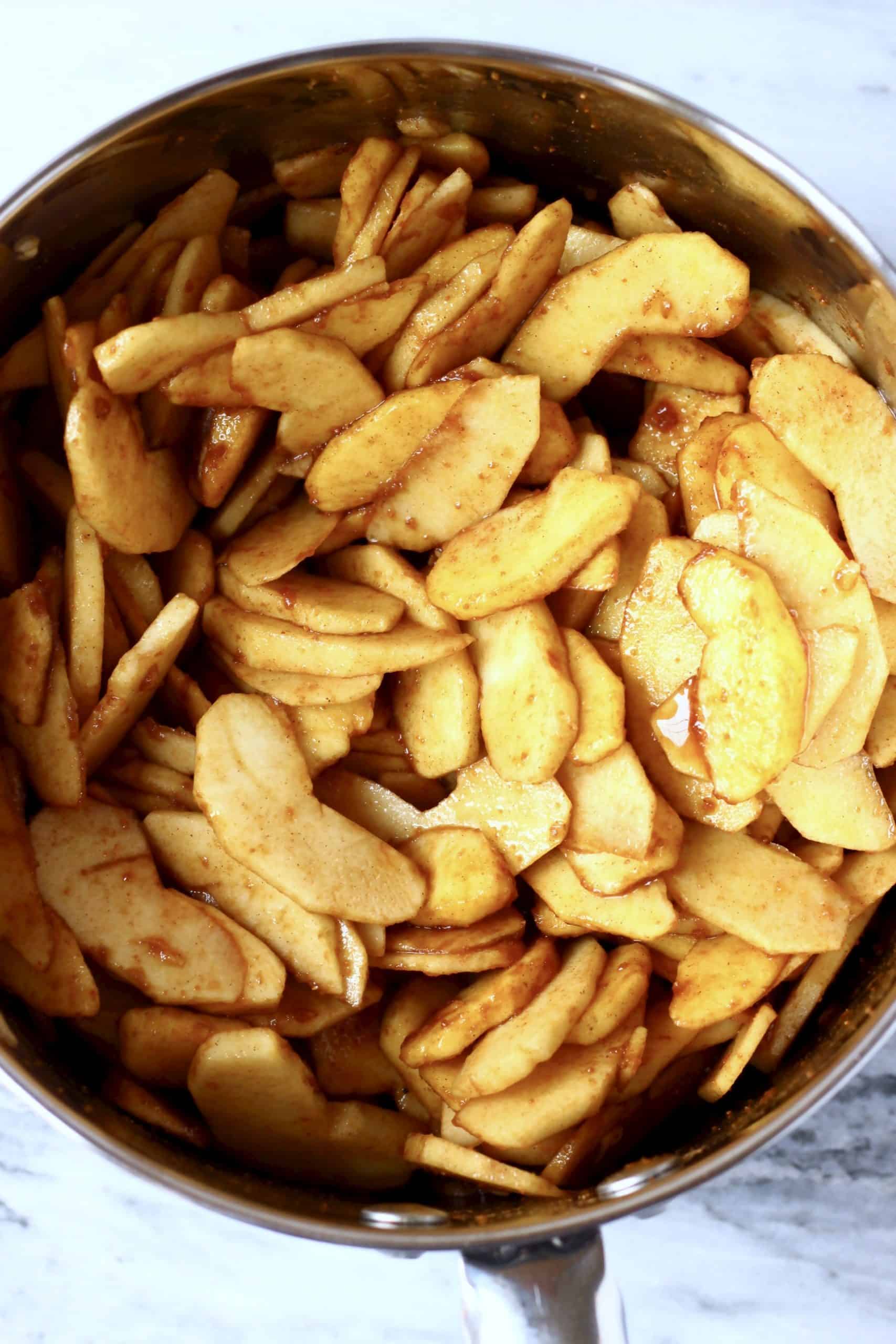 Sliced apples with cinnamon and coconut sugar in a silver pan
