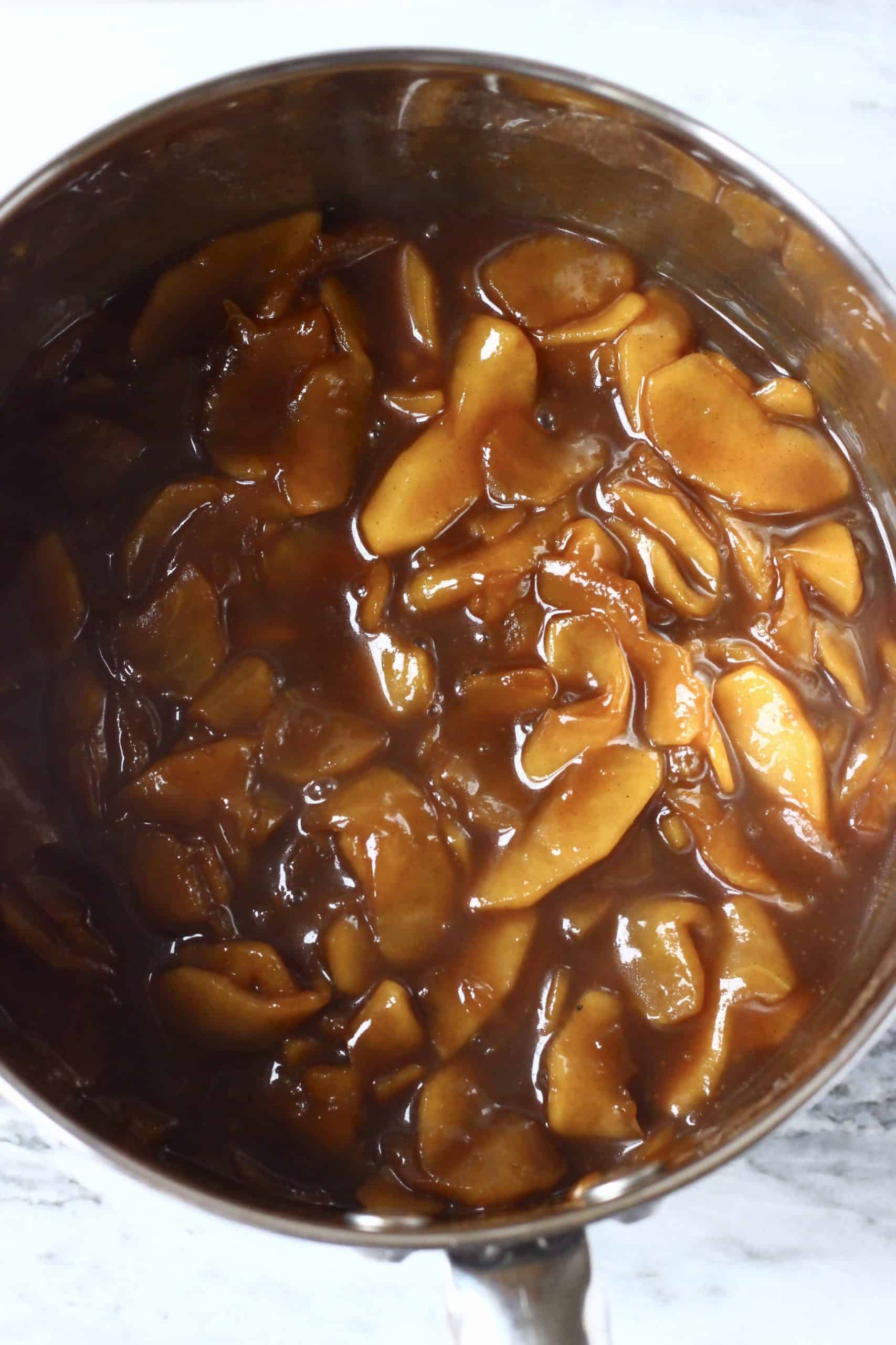 Cooked sliced apples with coconut sugar and cinnamon in a silver pan