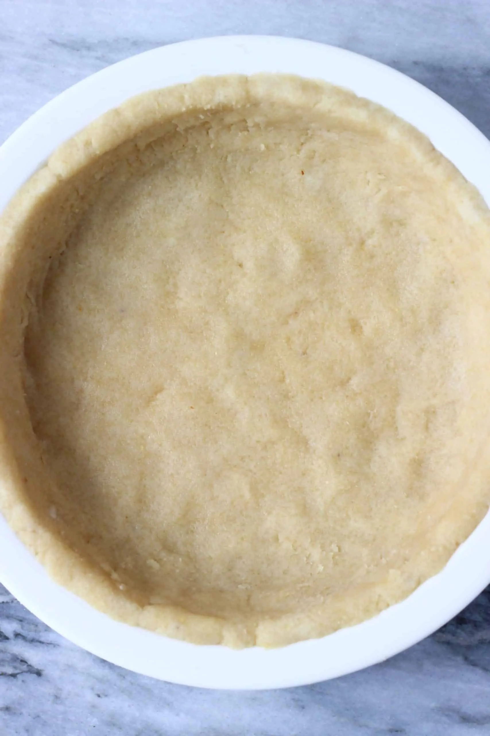 Raw gluten-free vegan pastry dough pressed along the bottom and sides of a pie dish