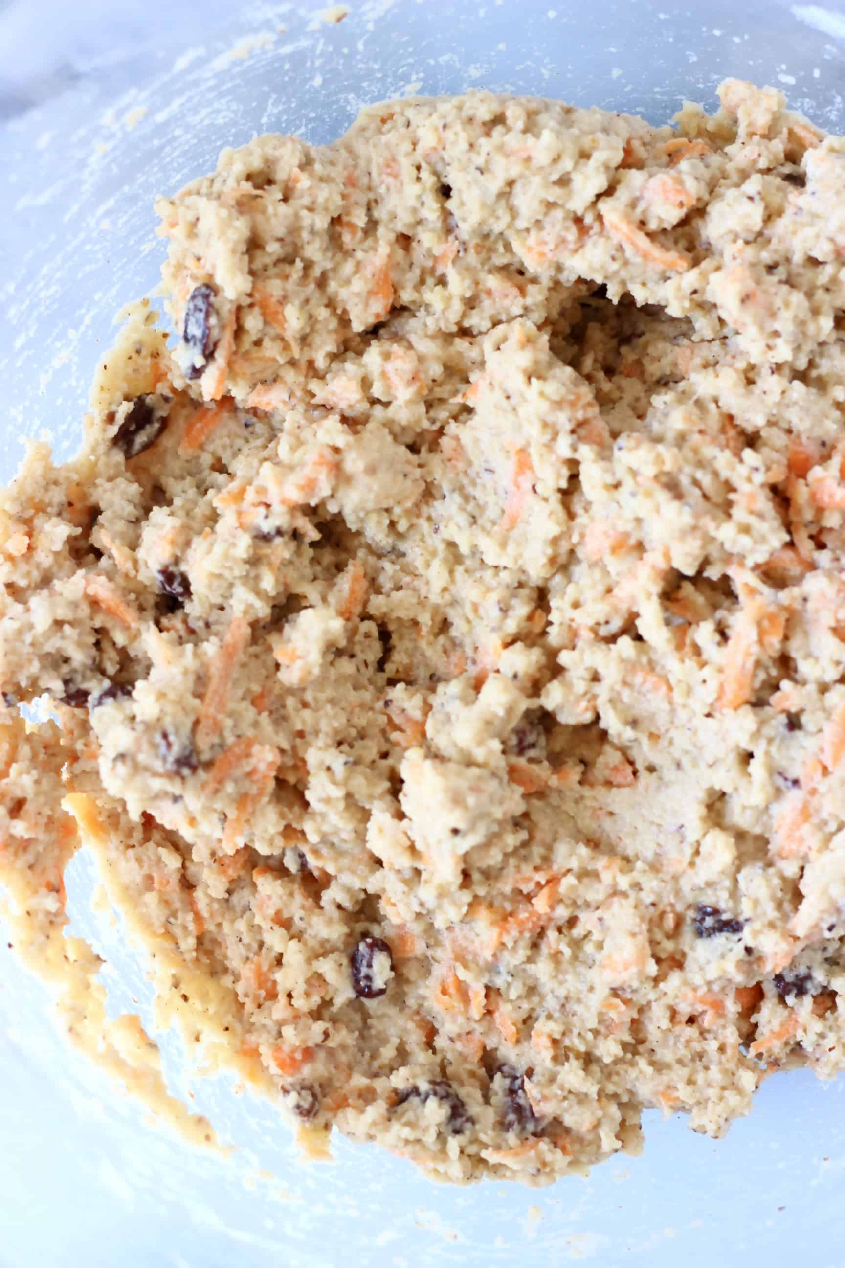 Raw vegan carrot cake batter in a glass mixing bowl