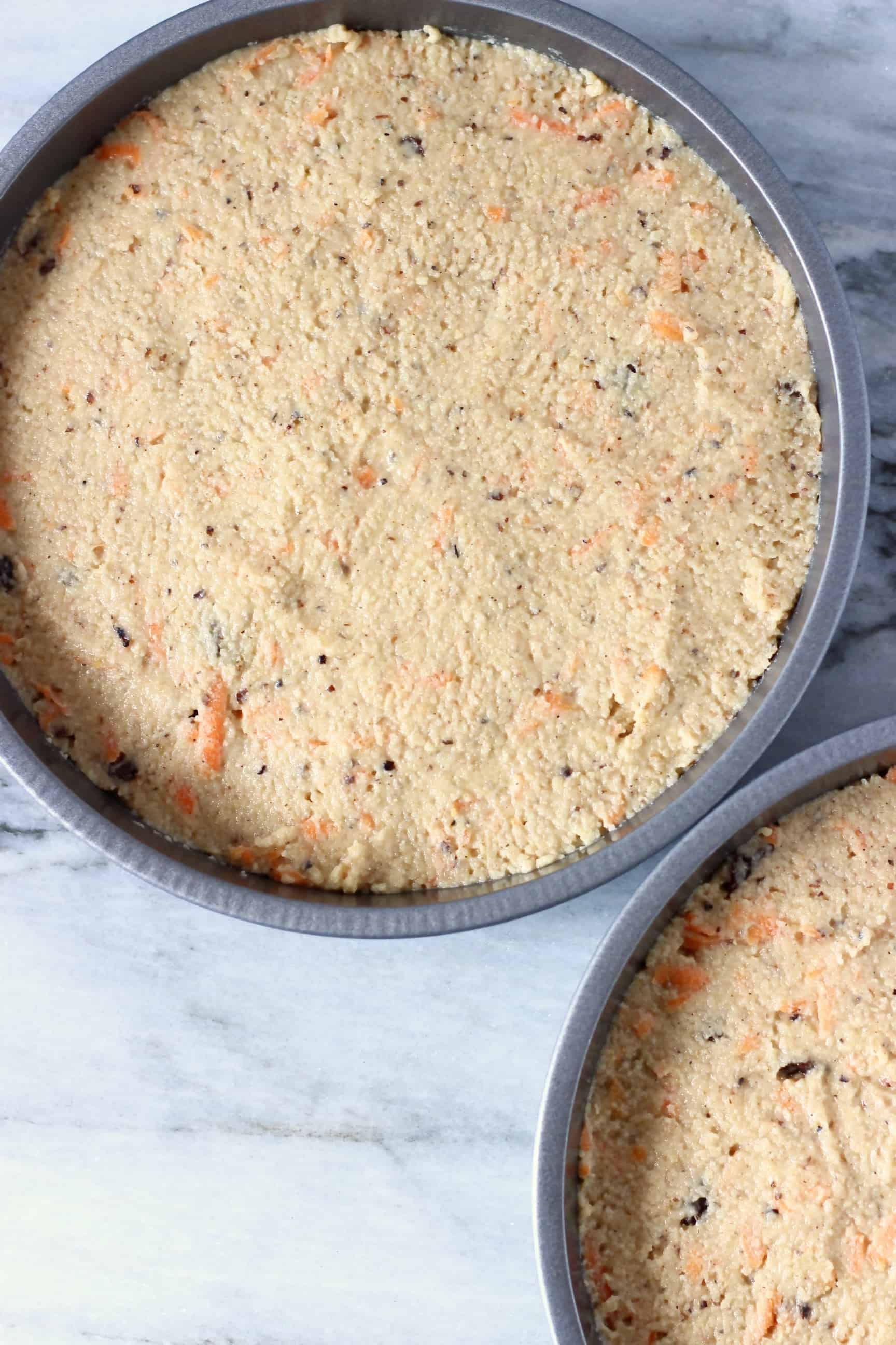 Two baking tins filled with raw vegan carrot cake batter