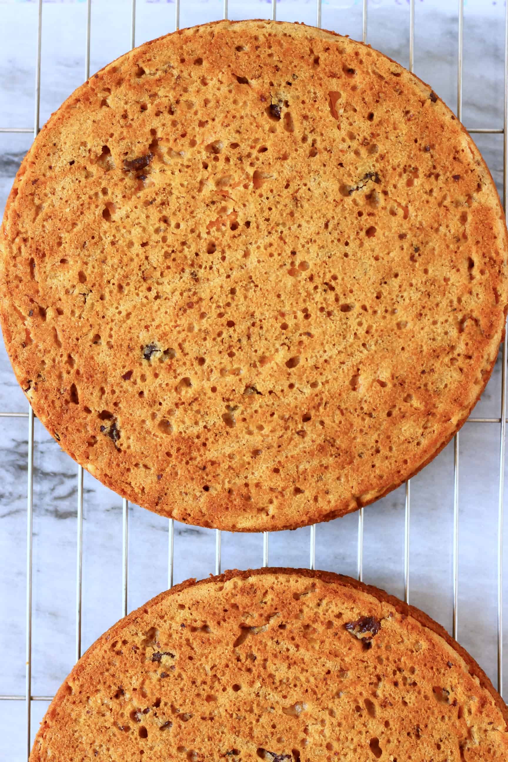 Two vegan carrot cake sponges on a wire rack against a marble background