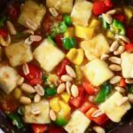 Photo of tofu cubes, peppers and peanuts in a frying pan