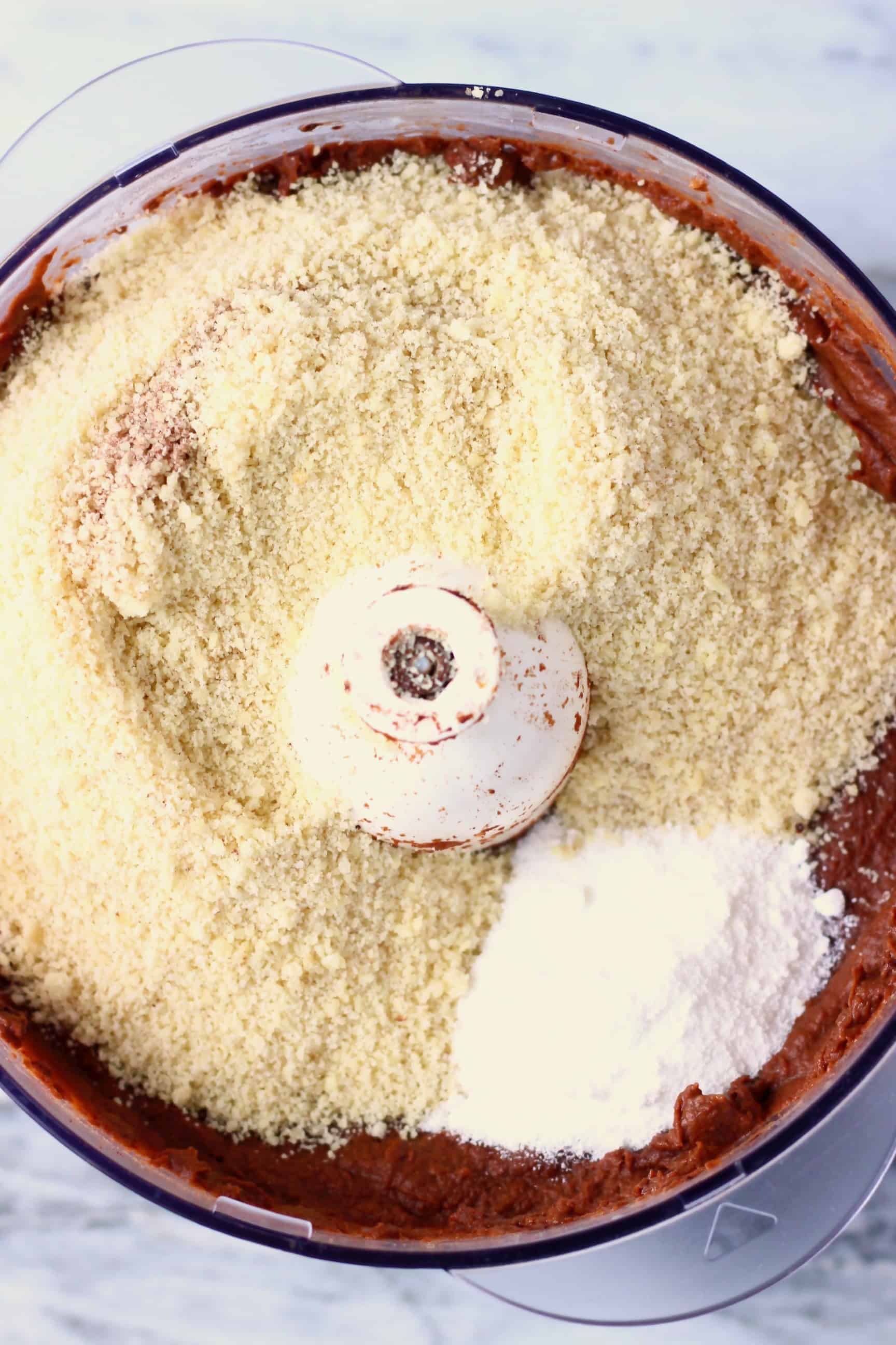 These Sweet Potato Brownies are seriously fudgy, rich and indulgent. They're made in just one bowl (food processor) and are vegan, dairy-free, egg-free, gluten-free, grain-free, refined sugar free, date-sweetened and oil-free. The best healthy dessert! #rhiansrecipes #vegan #brownies #sweetpotato #dessert #gluten-free #dairyfree #grainfree #oilfree Sweet potato brownie batter with ground almonds and baking powder in a food processor