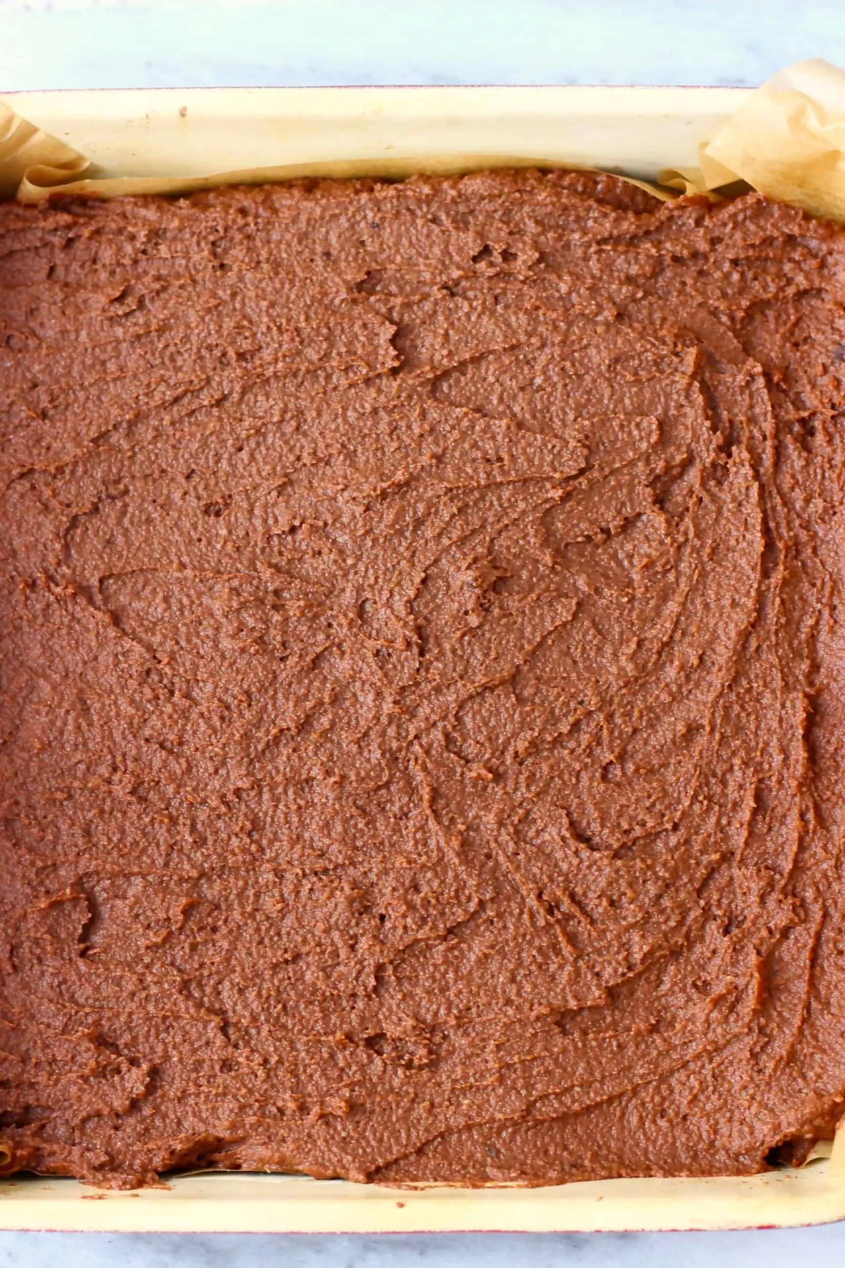 Raw sweet potato brownie batter in a baking tin lined with baking paper