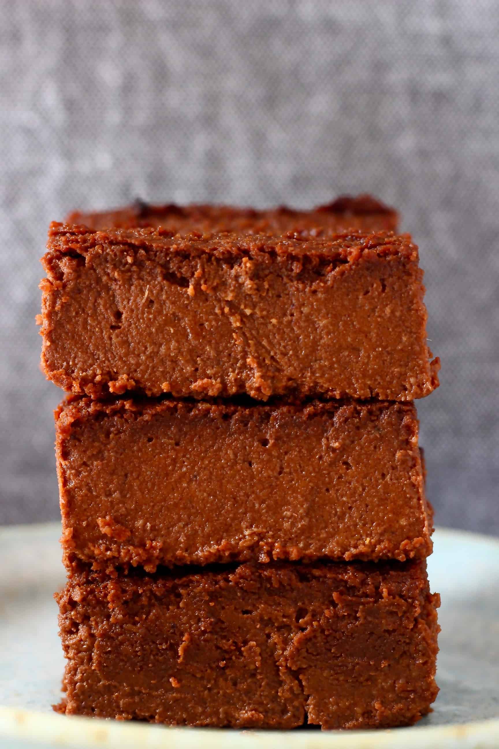 These Sweet Potato Brownies are seriously fudgy, rich and indulgent. They're made in just one bowl (food processor) and are vegan, dairy-free, egg-free, gluten-free, grain-free, refined sugar free, date-sweetened and oil-free. The best healthy dessert! #rhiansrecipes #vegan #brownies #sweetpotato #dessert #gluten-free #dairyfree #grainfree #oilfree Three sweet potato brownies stacked on top of each other on a plate