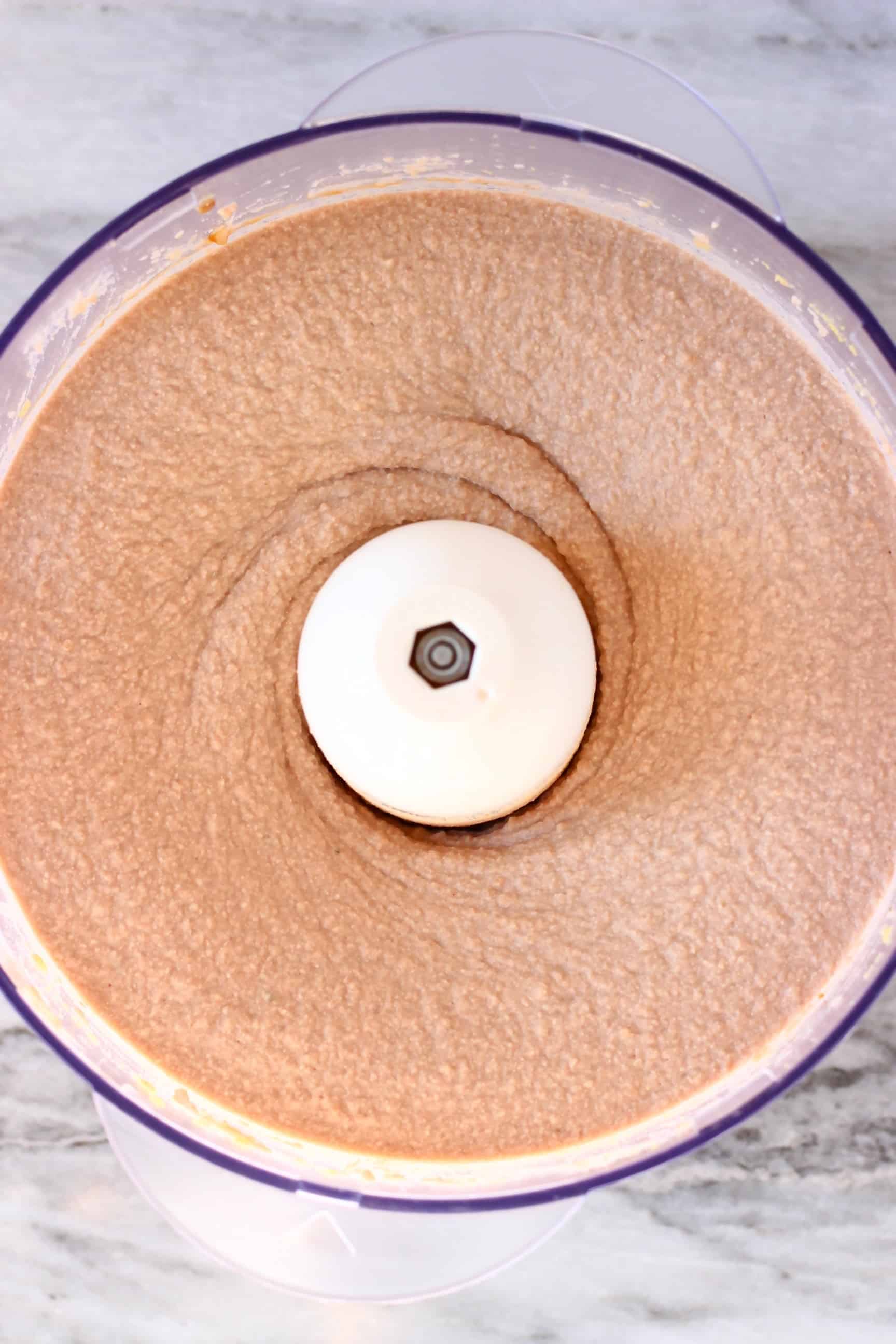A smooth beige paste in a food processor against a marble background