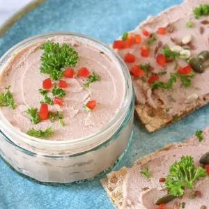 Pâté in a glass jar with two crackers spread with pâté on a blue plate