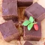 Five squares of vegan chocolate fudge on a sheet of baking paper