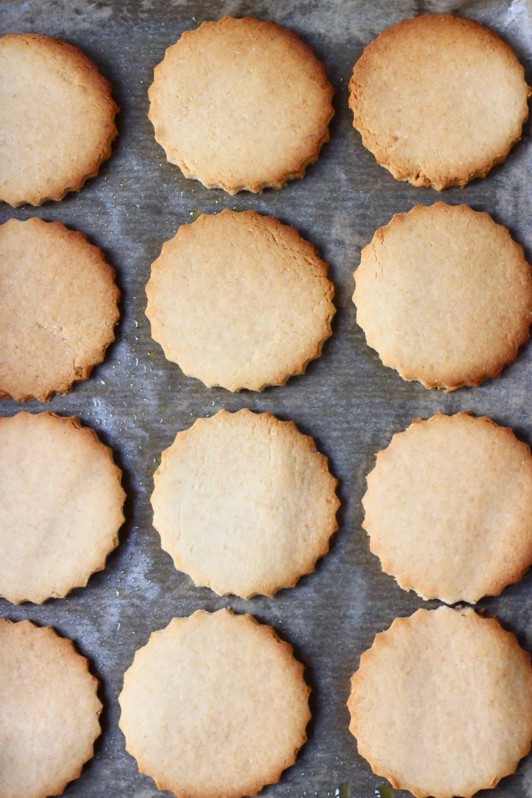 Twelve golden brown gluten-free vegan sugar cookies on a sheet of brown baking paper