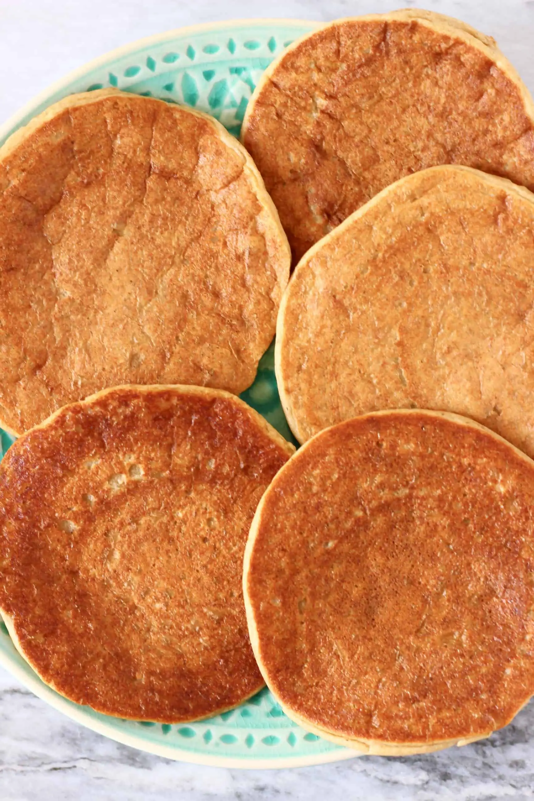 Five gluten-free vegan protein pancakes on a green plate 