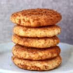 Five gluten-free vegan snickerdoodles stacked on top of each other on a plate