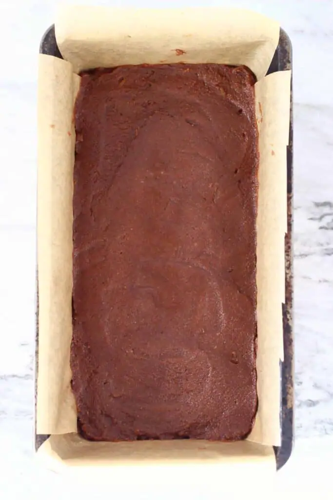 Photo of chocolate fudge mixture in a black loaf tin lined with brown baking paper