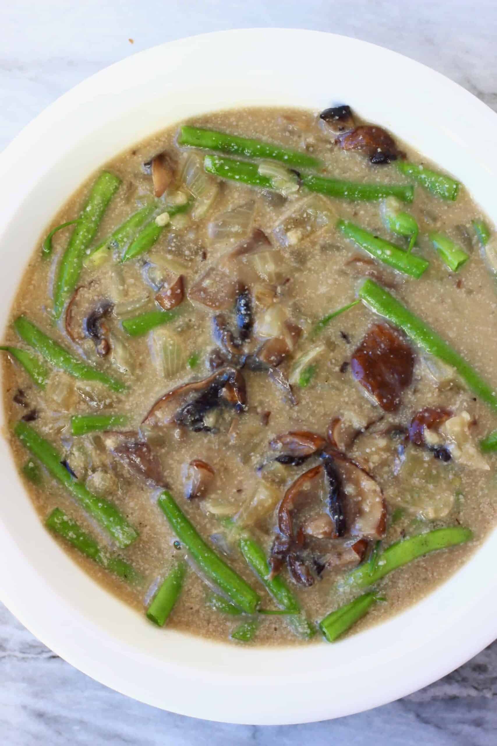 Brown creamy mushroom sauce and green beans in a pie dish