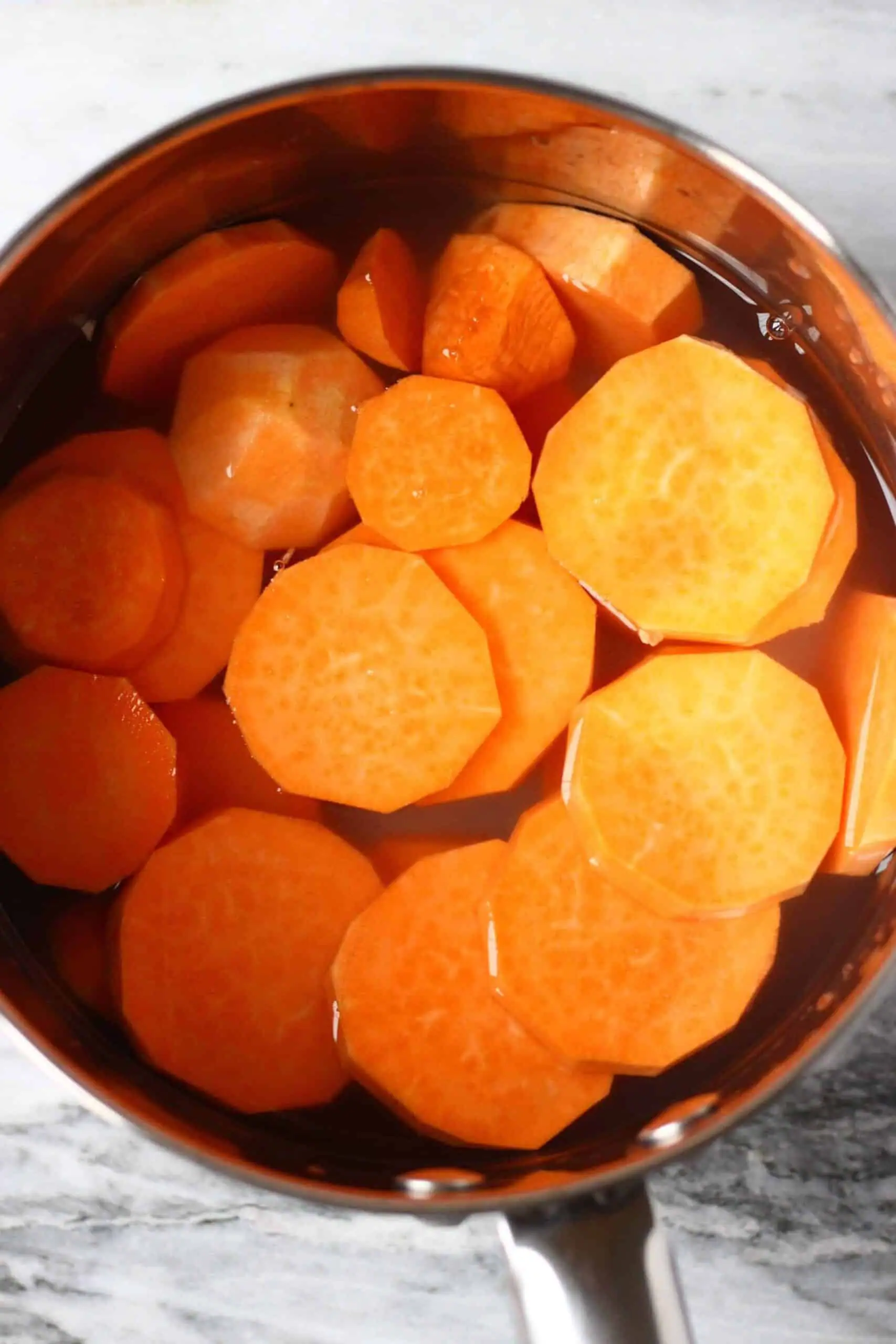 Sliced sweet potatoes covered in water in a pan 