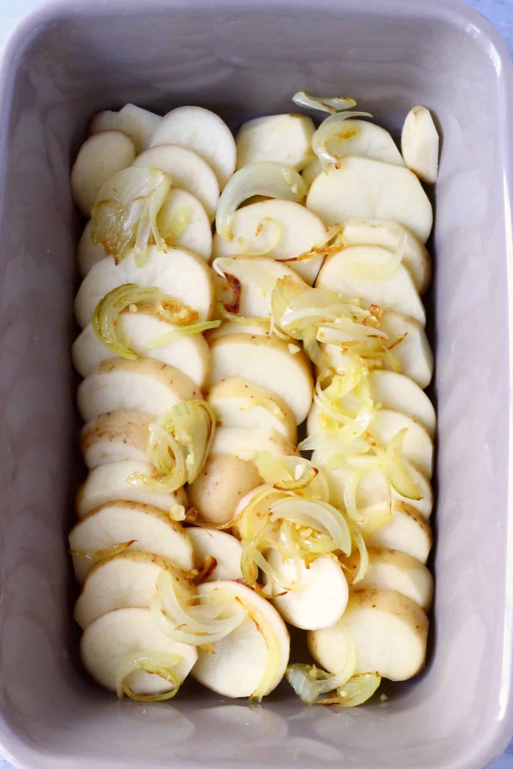 Sliced potatoes topped with fried onions in a baking dish