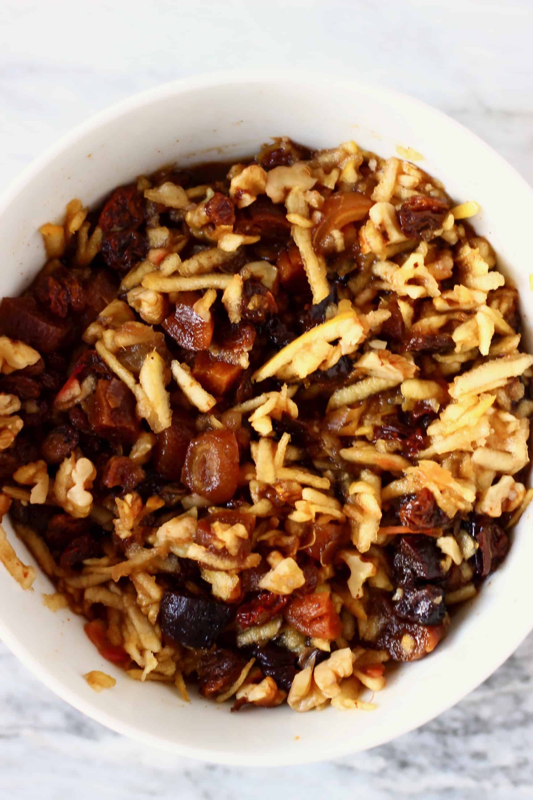 Chopped dried fruits and and grated apple soaked in sherry in a bowl to make vegan mincemeat 