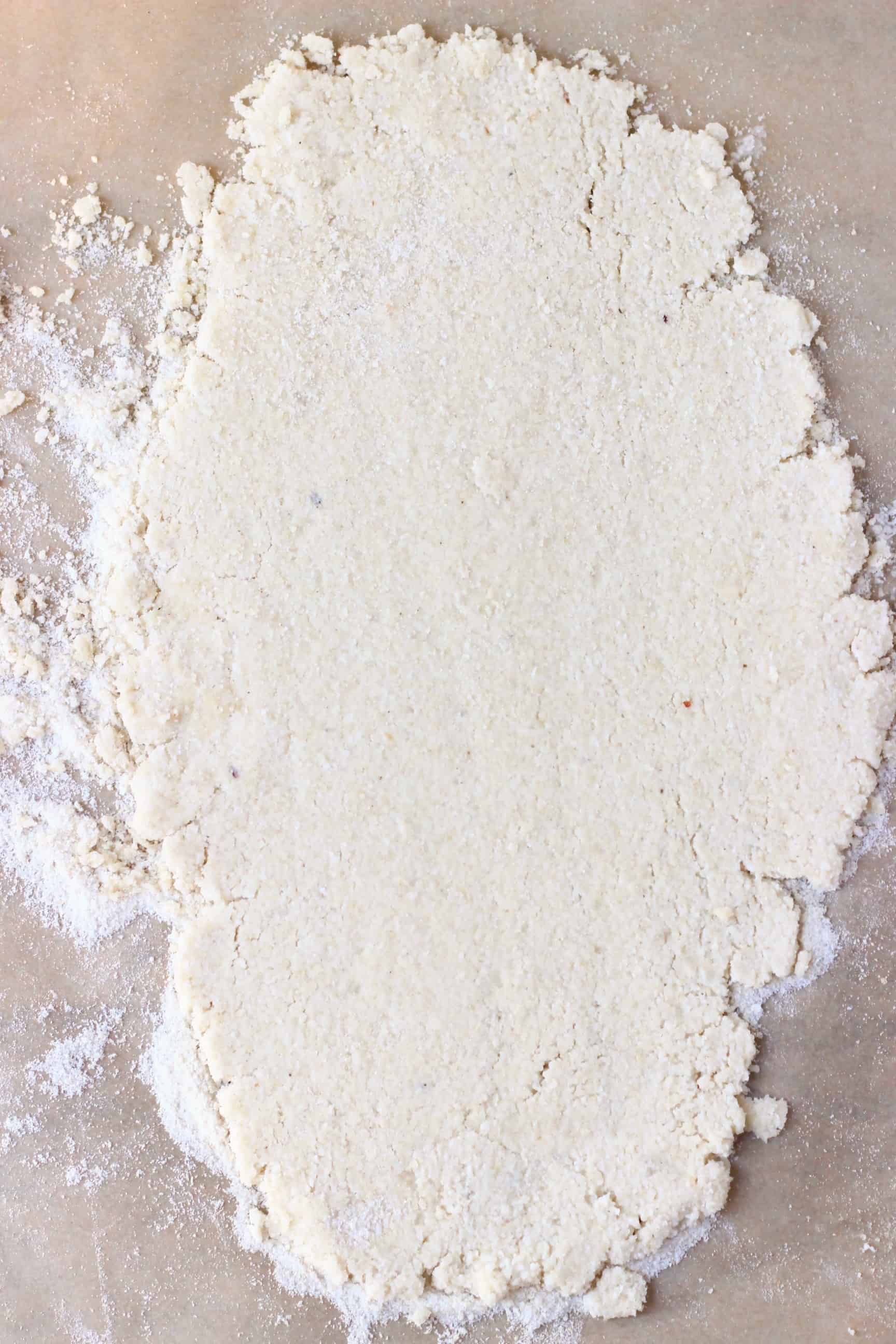 These Gluten-Free Vegan Mince Pies are crispy, flaky, fruity and fragrant - the best festive sweet treat for Christmas! Dairy-free, vegetarian, egg-free and refined sugar free. #rhiansrecipes #christmas #mincepies #vegan #dairyfree #glutenfree #dessert Gluten-free vegan pastry dough rolled out on a sheet of baking paper covered with flour