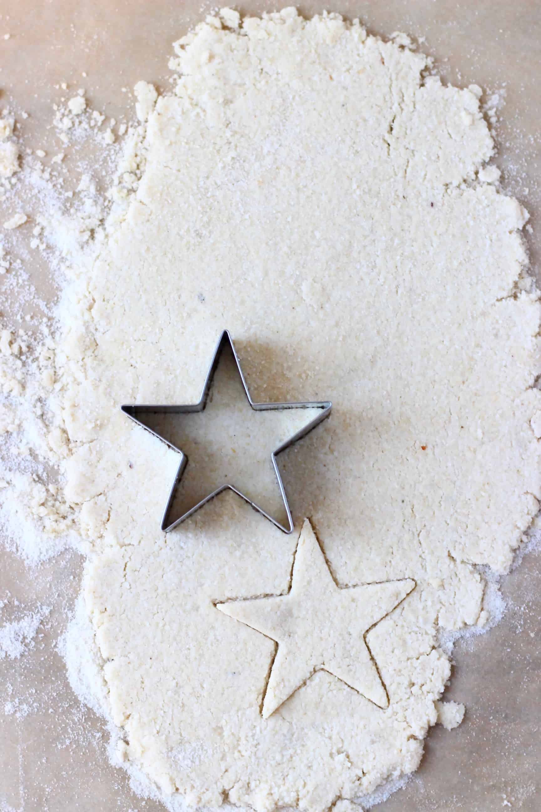 These Gluten-Free Vegan Mince Pies are crispy, flaky, fruity and fragrant - the best festive sweet treat for Christmas! Dairy-free, vegetarian, egg-free and refined sugar free. #rhiansrecipes #christmas #mincepies #vegan #dairyfree #glutenfree #dessert Gluten-free vegan pastry dough rolled out on a sheet of baking paper with a star-shaped cookie cutter on it