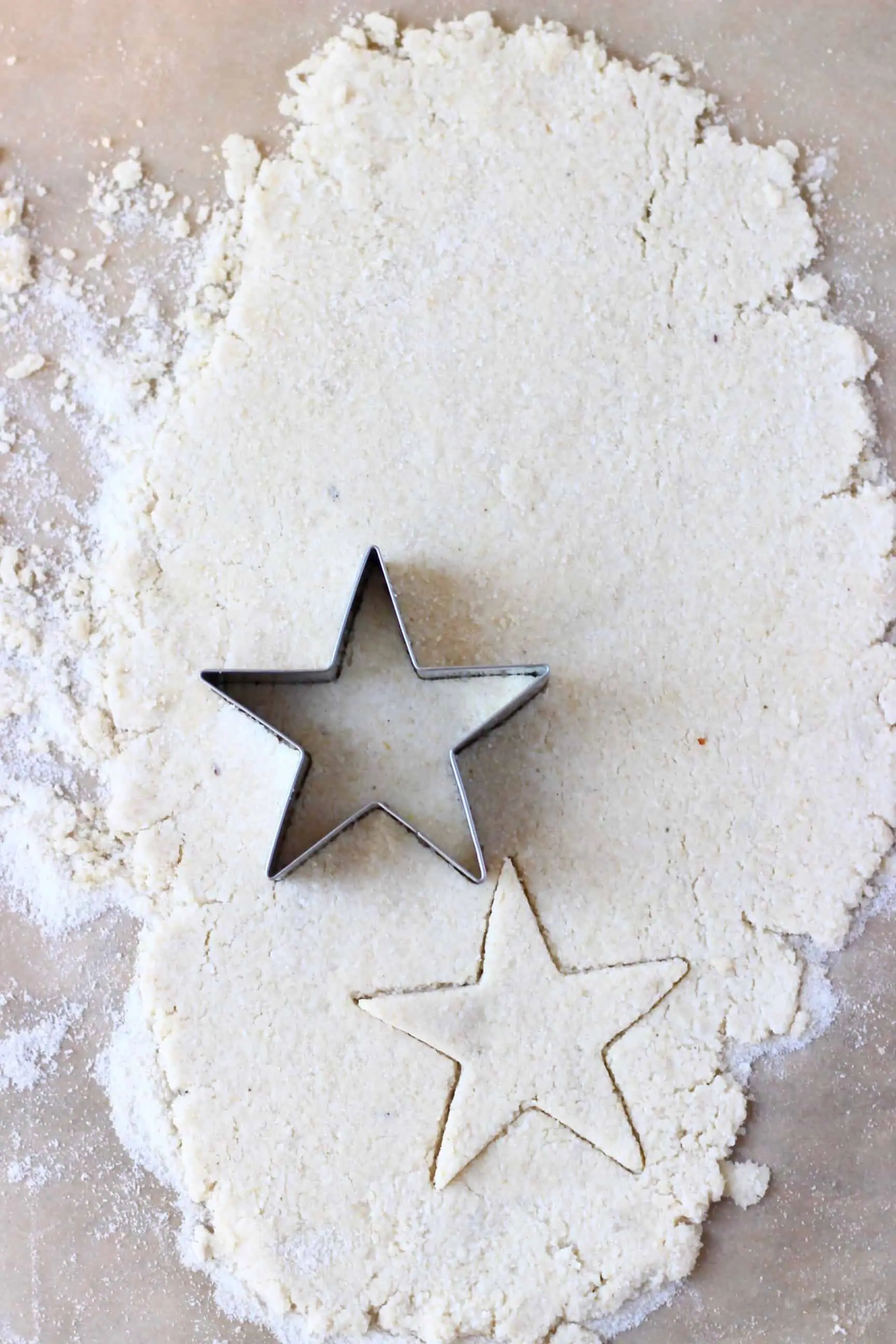 Gluten-free vegan pastry dough rolled out on a sheet of baking paper with a star-shaped cookie cutter on it