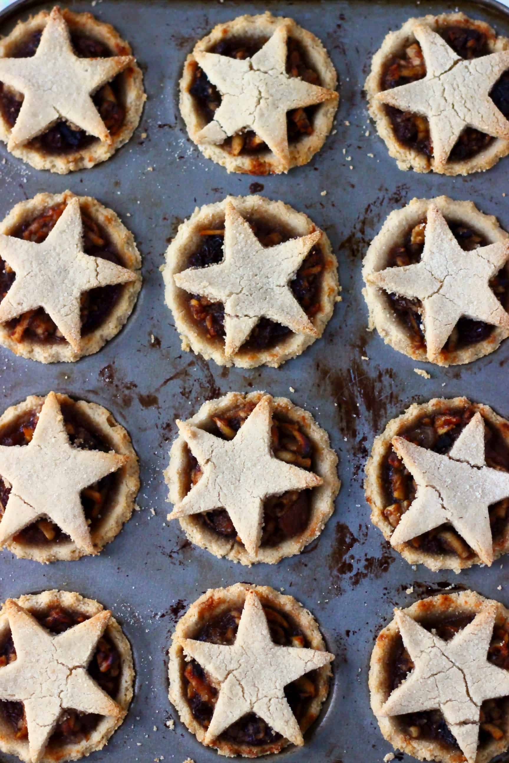 These Gluten-Free Vegan Mince Pies are crispy, flaky, fruity and fragrant - the best festive sweet treat for Christmas! Dairy-free, vegetarian, egg-free and refined sugar free. #rhiansrecipes #christmas #mincepies #vegan #dairyfree #glutenfree #dessert Twelve gluten-free vegan mince pies in a muffin tin topped with pastry stars