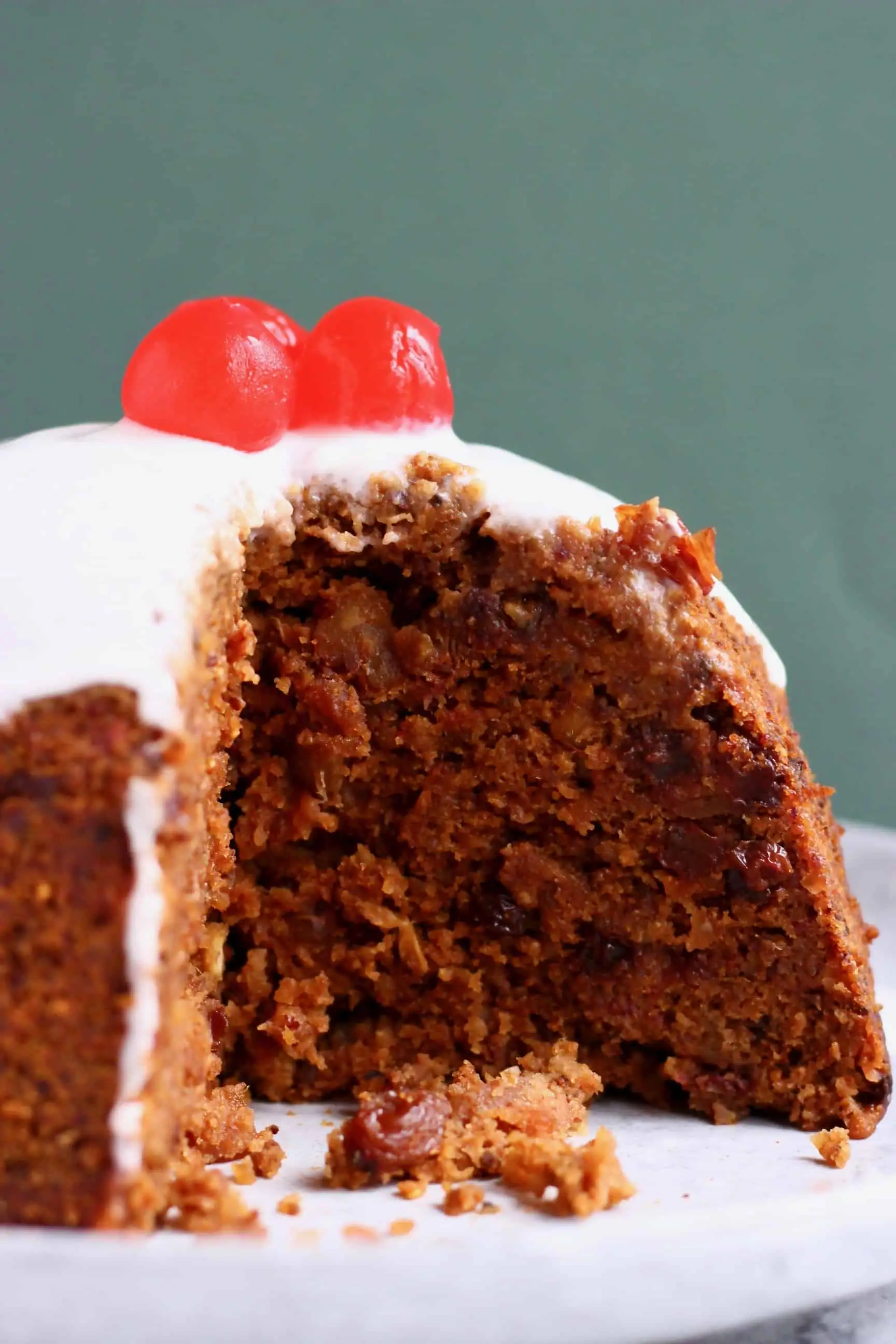 A round Christmas pudding with white cream poured over it topped with three bright red cherries 
