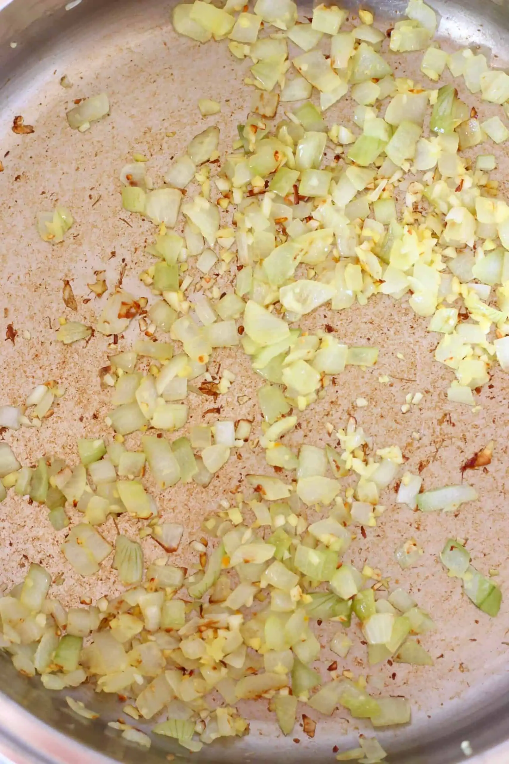 Diced onion being fried in a pan