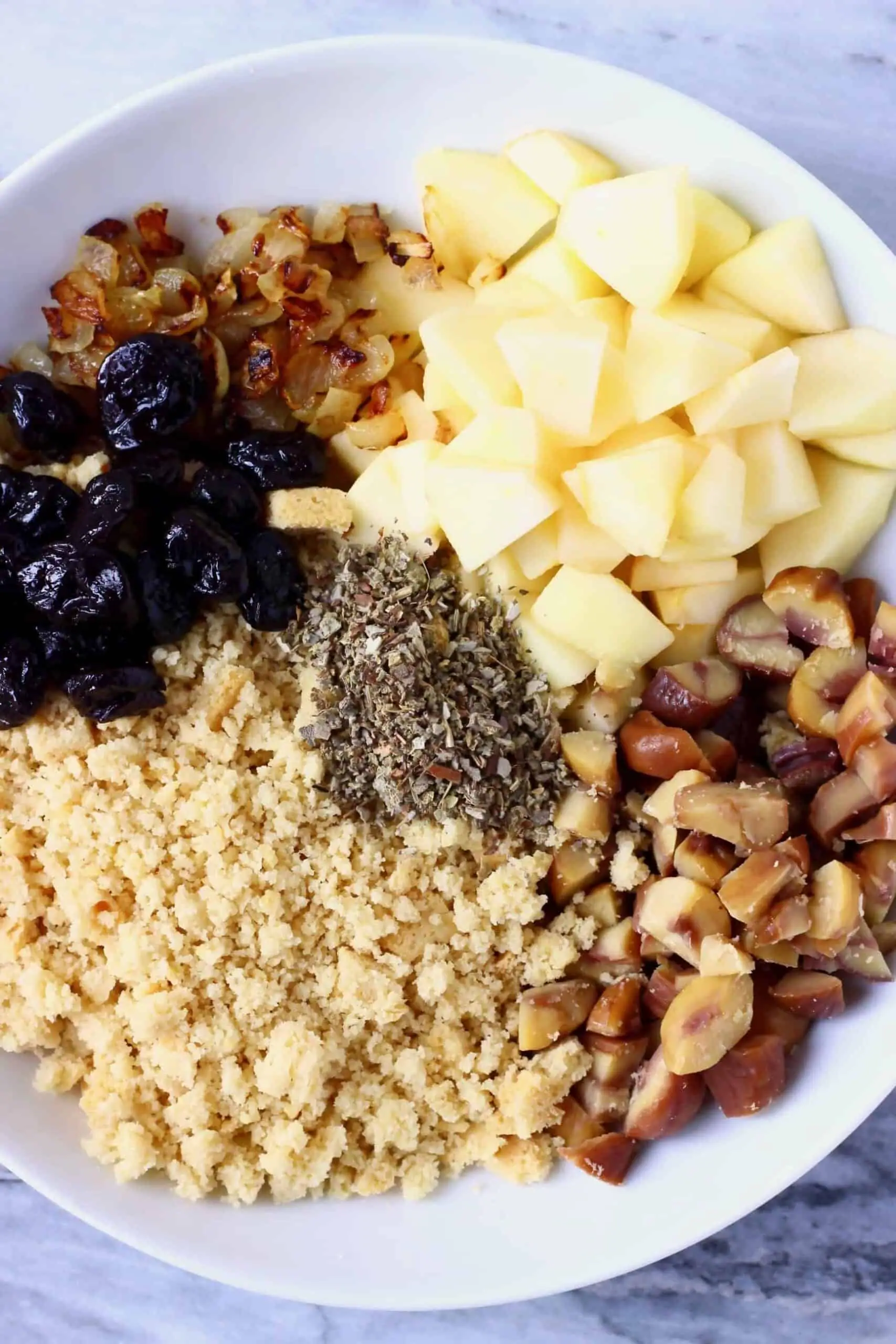 Diced apple, dried cherries, dried sage, chopped chestnuts, breadcrumbs and diced fried onion in a bowl