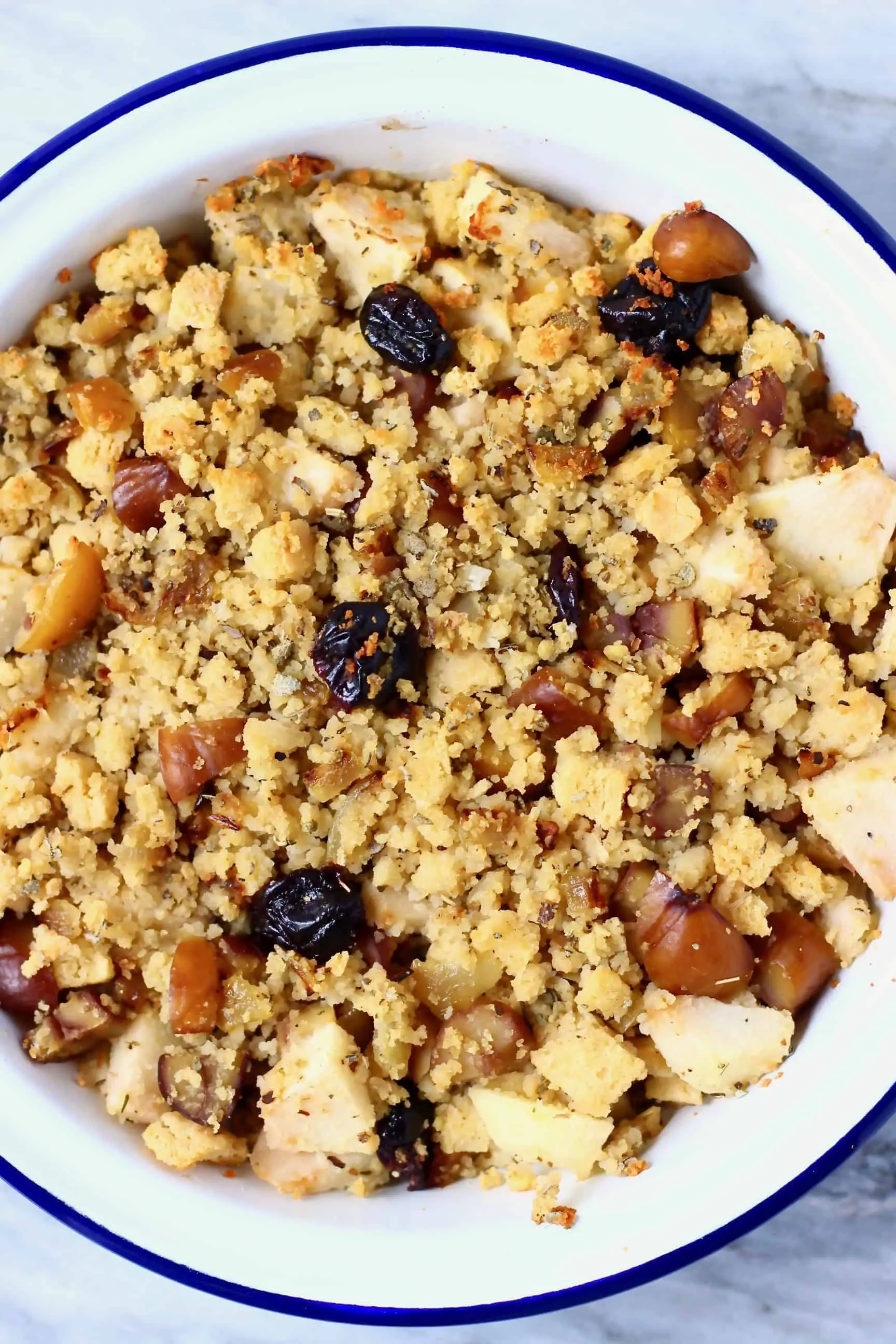 Vegan stuffing made with diced apple, dried cherries, dried sage, chopped chestnuts and breadcrumbs in a pie dish 