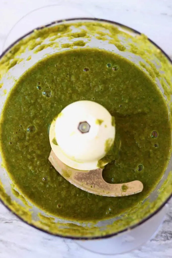 Photo of a green sauce in a food processor against a marble background
