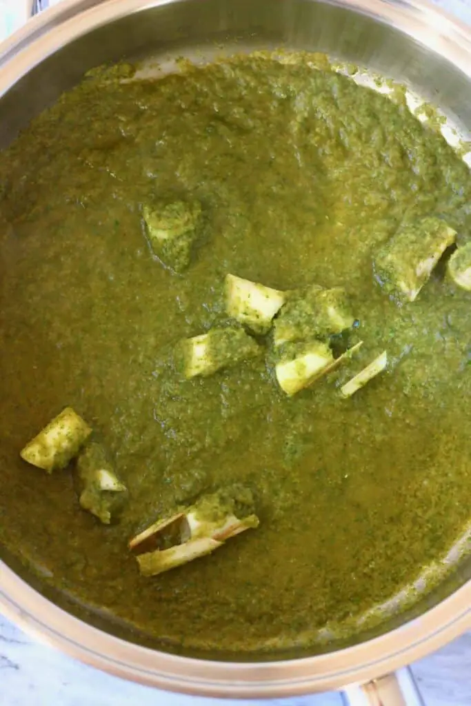 Photo of green curry paste and lemon grass stalks in a silver saucepan