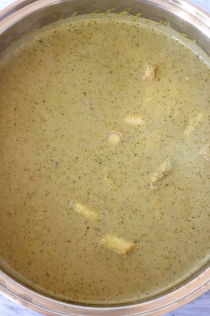 Photo of green curry paste, coconut milk and lemon grass stalks in a silver saucepan