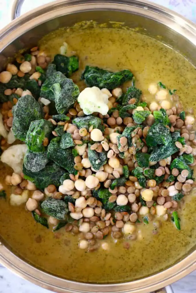 Photo of green curry sauce with frozen cauliflower, spinach, chickpeas and lentils in a silver saucepan