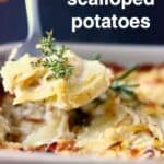 Photo of scalloped potatoes in a grey baking dish with a silver spoon lifting up a mouthful of it against a black background