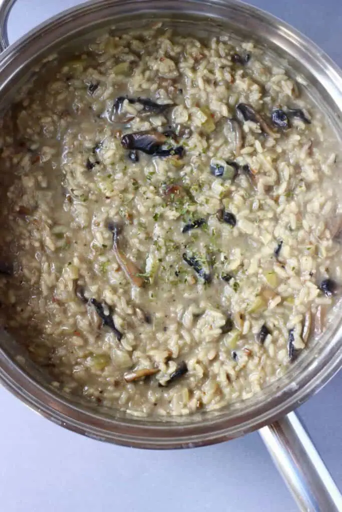 Mushroom risotto in a silver pan against a grey background