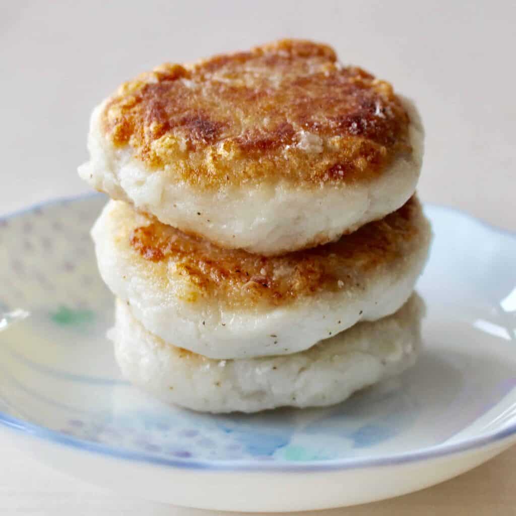 Three crispy taro fritters on a light blue plate against a white background