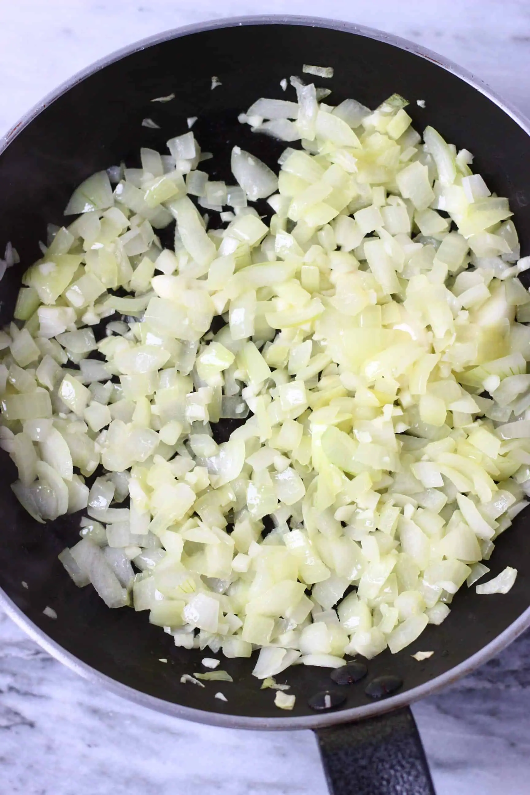 Diced onion and minced garlic being fried in a frying pan 