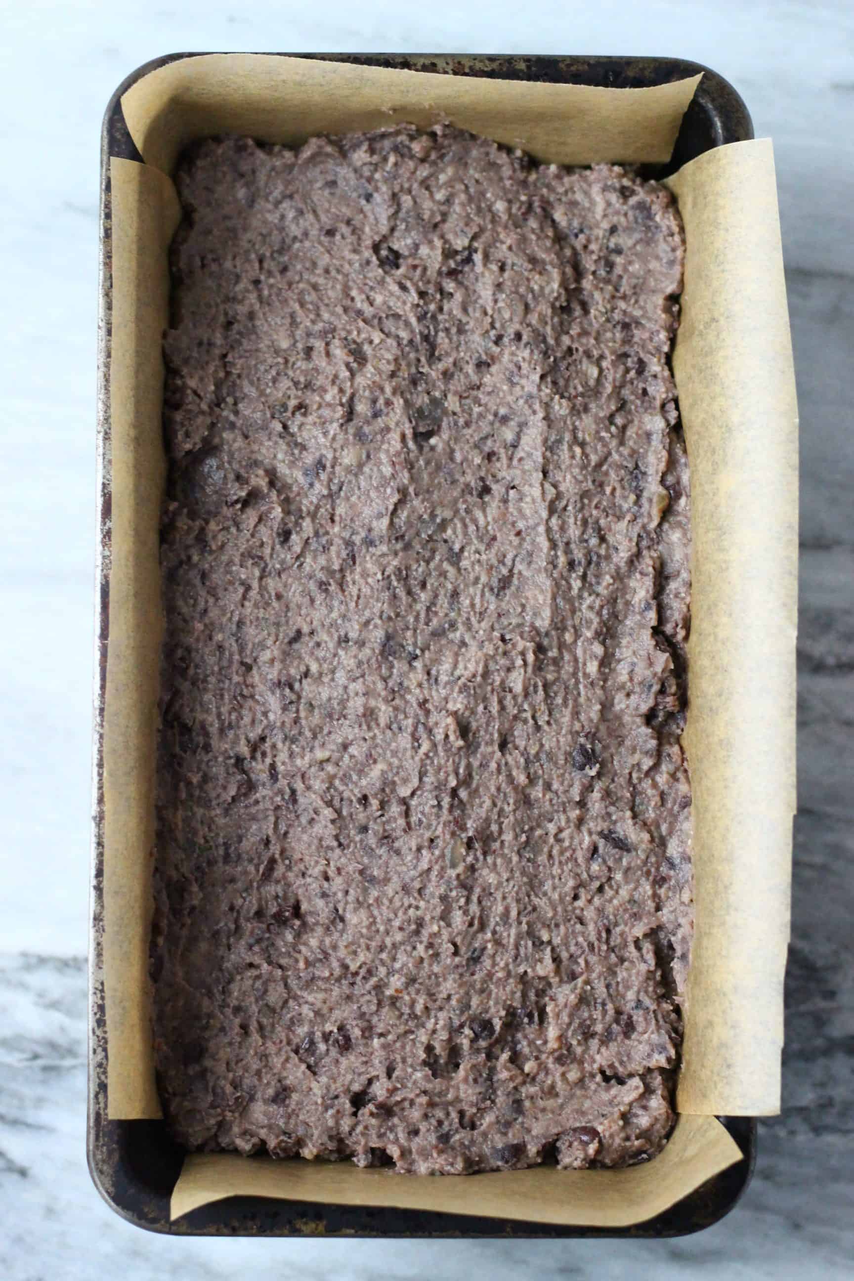 This Vegan Meatloaf is made with hearty black beans, earthy walnuts and savoury mushrooms - it's rich and flavourful, filling and satisfying and super easy to make! Perfect for Christmas, Thanksgiving and everything else in between! Vegetarian, gluten-free, dairy-free and egg-free. #rhiansrecipes #meatloaf #christmas #thanksgiving #vegan #dairyfree #glutenfree #vegetarian Vegan black bean meatloaf mixture in a loaf tin lined with baking paper