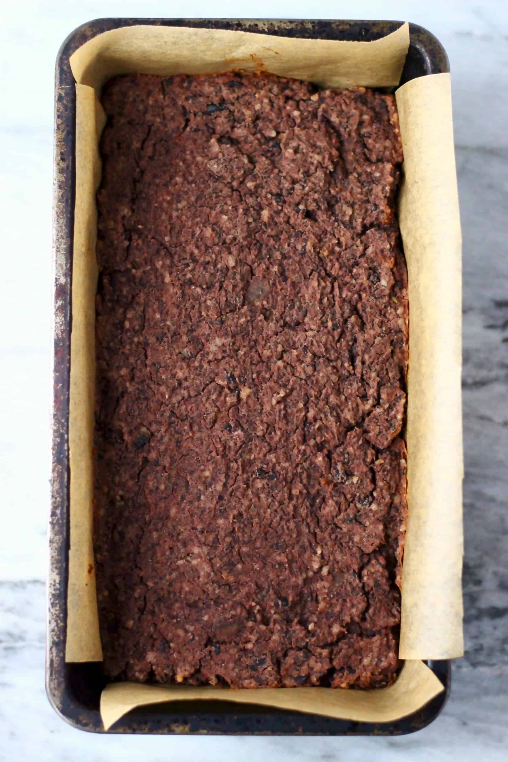 This Vegan Meatloaf is made with hearty black beans, earthy walnuts and savoury mushrooms - it's rich and flavourful, filling and satisfying and super easy to make! Perfect for Christmas, Thanksgiving and everything else in between! Vegetarian, gluten-free, dairy-free and egg-free. #rhiansrecipes #meatloaf #christmas #thanksgiving #vegan #dairyfree #glutenfree #vegetarian Cooked vegan black bean meatloaf in a loaf tin lined with baking paper