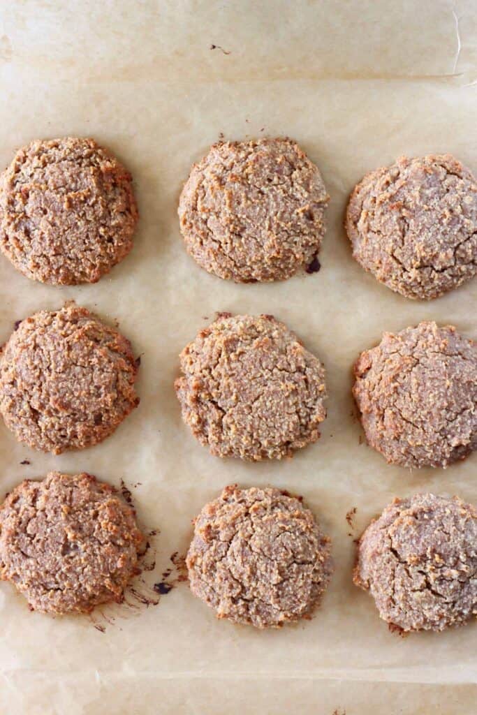 These Gluten-Free Vegan Ginger Cookies are soft and chewy, warmly spiced and perfectly sweet! The perfect festive treat for Christmas. Refined sugar free, oil-free, date-sweetened, grain-free and paleo-friendly. #rhiansrecipes #cookies #christmas #vegan #glutenfree #paleo #grainfree #ginger #baking #dessert #dairyfree Nine cooked golden brown cookies on a sheet of brown baking paper